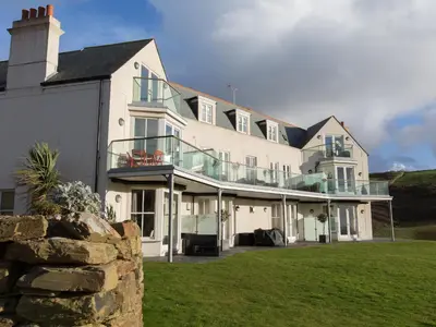 a large white building with a balcony on it at 9 The Whitehouse in Mawgan Porth
