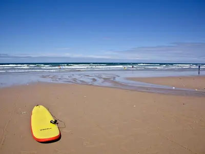 a yellow surfboard sitting on a sandy beach at 9 The Whitehouse in Mawgan Porth