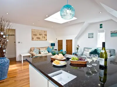 a kitchen and living room with a table with a bottle of wine at 9 The Whitehouse in Mawgan Porth