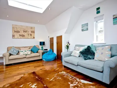 a living room with two couches and a rug at 9 The Whitehouse in Mawgan Porth