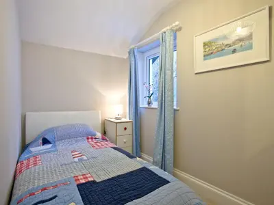 a small bedroom with a bed and a window at Kerensa in Looe