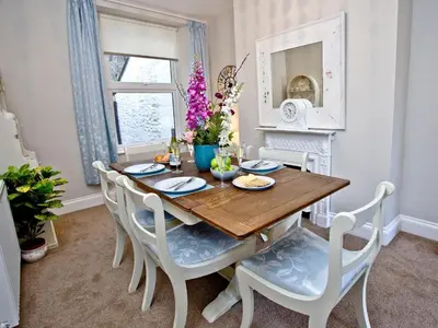 a dining room with a wooden table and white chairs at Kerensa in Looe