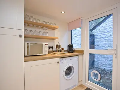 a kitchen with a washer and dryer and a window at Kerensa in Looe