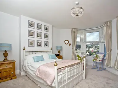 a bedroom with a white bed and a window at Kerensa in Looe