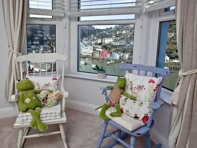 two chairs and a teddy bear in a room with windows at Kerensa in Looe