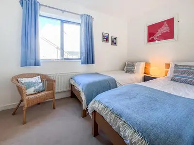 a bedroom with two beds and a chair and a window at 3 Waterwheel Apartment in Charlestown