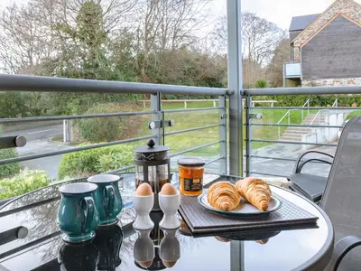 a table with a tray of croissants and eggs on a balcony at 3 Waterwheel Apartment in Charlestown