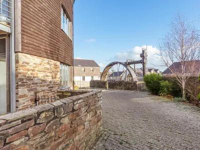 a brick wall next to a building and a bridge at 3 Waterwheel Apartment in Charlestown