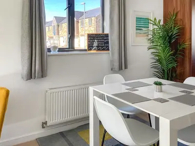 a white dining room with a white table and chairs at 3 Waterwheel Apartment in Charlestown