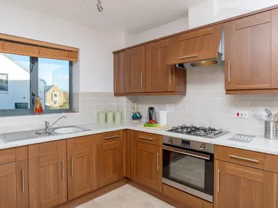 a kitchen with wooden cabinets and a stove top oven at 3 Waterwheel Apartment in Charlestown
