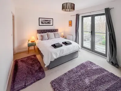 a bedroom with a large bed with purple rugs at 3 Waterwheel Apartment in Charlestown
