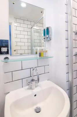 a white bathroom with a sink and a mirror at The Slipway B&B in Port Isaac