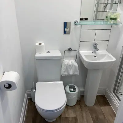 a white bathroom with a toilet and a sink at The Slipway B&B in Port Isaac