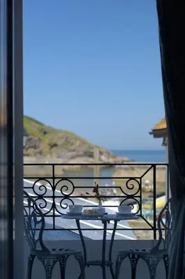 a table and chairs on a balcony with a view of the ocean at The Slipway B&B in Port Isaac