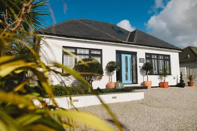 a white house with black windows and potted plants at Haven Lodge Newquay in Newquay