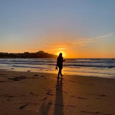 a person walking on the beach at sunset at Penwyth House in Newquay