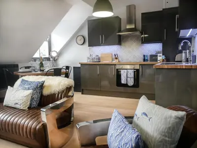 a living room with a couch and a kitchen at Padstow Escapes - Pajar Luxury Penthouse Apartment in Padstow