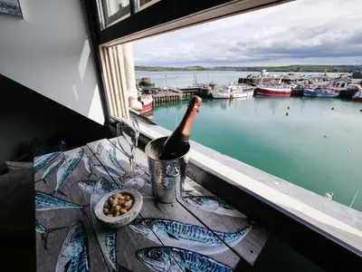 a bottle of wine sitting on a window sill at Padstow Escapes - Pajar Luxury Penthouse Apartment in Padstow
