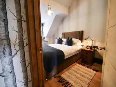 a bedroom with a bed and a tree mural on the wall at Padstow Escapes - Pajar Luxury Penthouse Apartment in Padstow