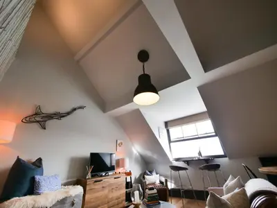a living room with a couch and a tv and a ceiling at Padstow Escapes - Pajar Luxury Penthouse Apartment in Padstow