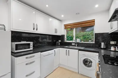 a kitchen with white cabinets and a sink and a microwave at Tincroft Cottage - high end, luxury living near the beach in Truro