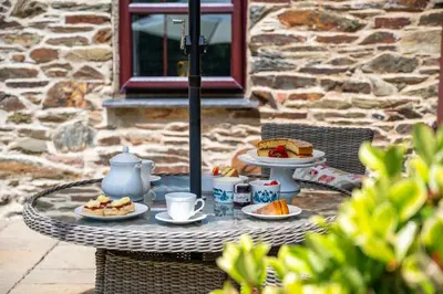 a table with plates of food and coffee on it at Callestock Courtyard Cottages in Truro