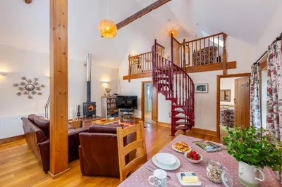 a living room with a couch and a spiral staircase at Callestock Courtyard Cottages in Truro