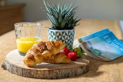 a table with a croissant and strawberries and a glass of orange juice at Callestock Courtyard Cottages in Truro