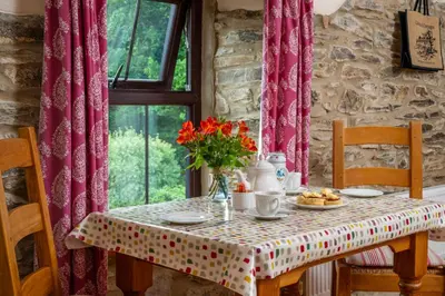 a table with a vase of flowers on it at Callestock Courtyard Cottages in Truro