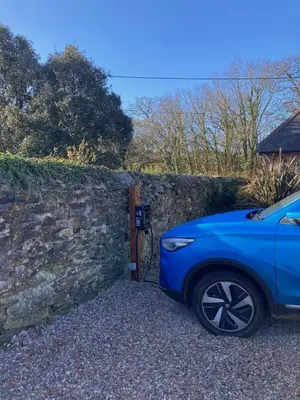 a blue car parked next to a stone wall at Callestock Courtyard Cottages in Truro
