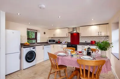 a kitchen with a table and chairs and a kitchen with white appliances at Callestock Courtyard Cottages in Truro