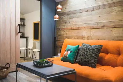 a living room with an orange couch and a table at An Leti @ Goonwinnow Farm in Newquay