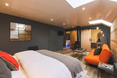 a bedroom with a bed and an orange chair at An Leti @ Goonwinnow Farm in Newquay