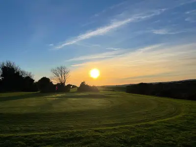 a sunset on a golf course with the sun setting at Wheal Rose -Beautifully Fitted Lodge Helston Cornwall in Helston