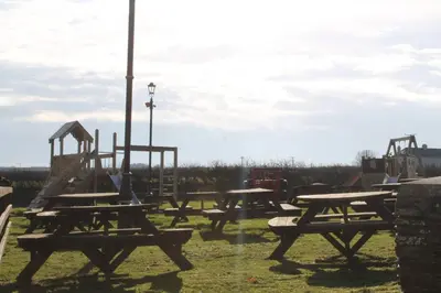 a group of picnic tables with a playground at The Pickwick Inn & Oliver's Restaurant in Padstow