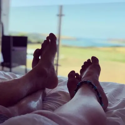 a person with their feet up on a bed at The Pickwick Inn & Oliver's Restaurant in Padstow