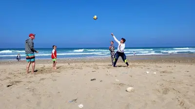 a group of people playing with a frisbee on the beach at Beach View Apartments in Porthtowan