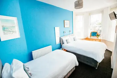 a room with two beds and a blue wall at Surfside Stop in Newquay