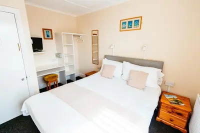 a bedroom with a white bed and a desk at Surfside Stop in Newquay