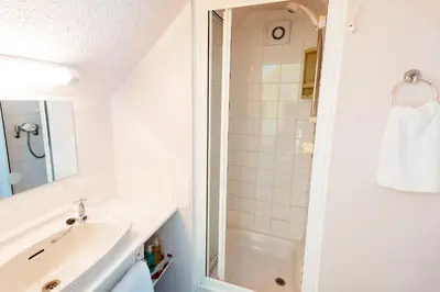 a white bathroom with a sink and a shower at Surfside Stop in Newquay