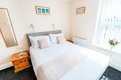 a bedroom with a white bed and a window at Surfside Stop in Newquay