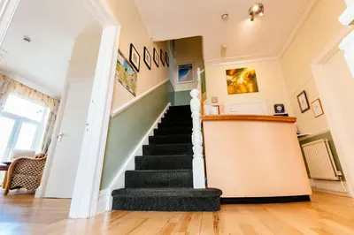 a staircase in a home with green walls and wooden floors at Surfside Stop in Newquay