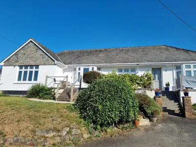 a white house with a porch and stairs at Halwyn Retreat in St Austell