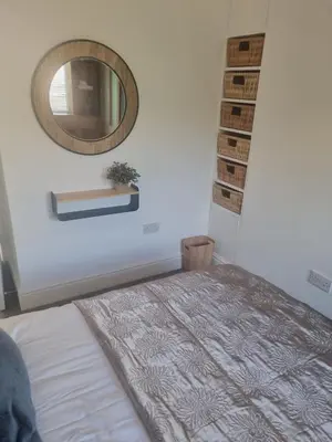 a bedroom with a bed and a mirror on the wall at Halwyn Retreat in St Austell