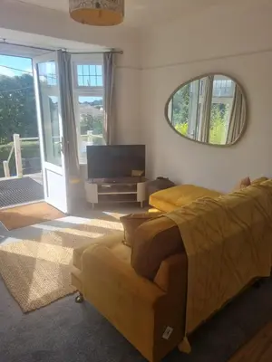 a living room with a couch and a tv and a mirror at Halwyn Retreat in St Austell