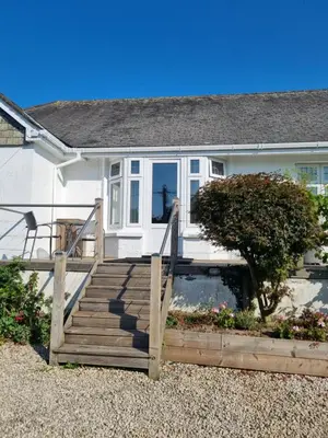 a house with a wooden staircase in front of it at Halwyn Retreat in St Austell