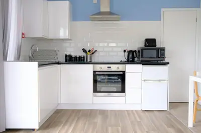 a kitchen with white cabinets and a microwave at Cornish Coasts Holiday Park in Bude