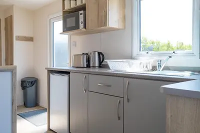 a kitchen with white cabinets and a sink and a window at Cornish Coasts Holiday Park in Bude