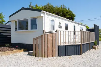 a small white house with a wooden fence at Cornish Coasts Holiday Park in Bude