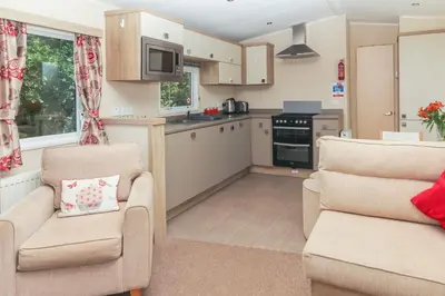 a living room with two chairs and a kitchen at Cornish Coasts Holiday Park in Bude
